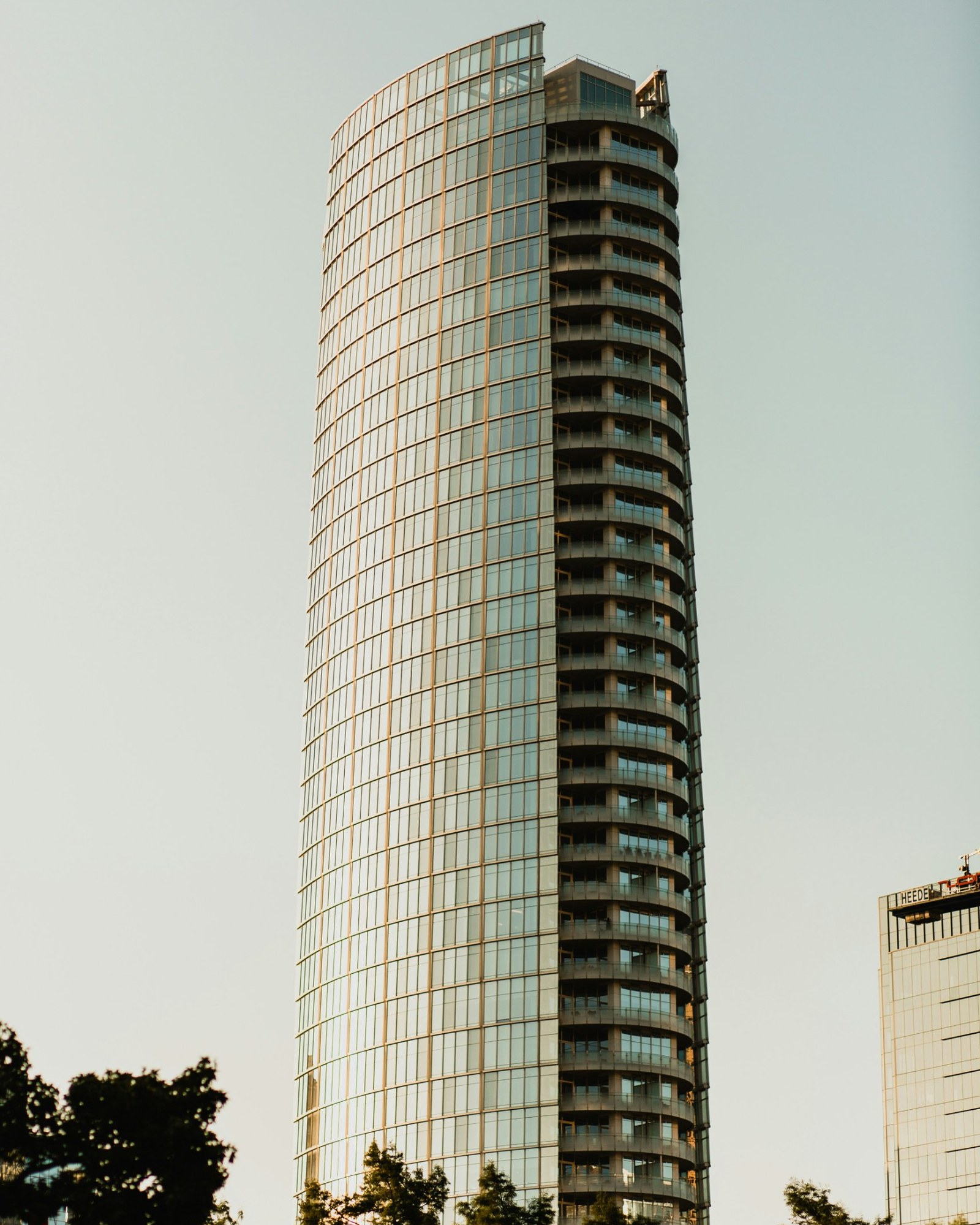 Tall curved glass tower against the sky at sunset